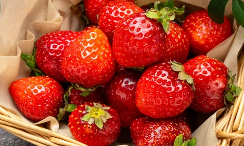 Frische Erdbeeren neben einem Glas Erdbeerkonfitüre